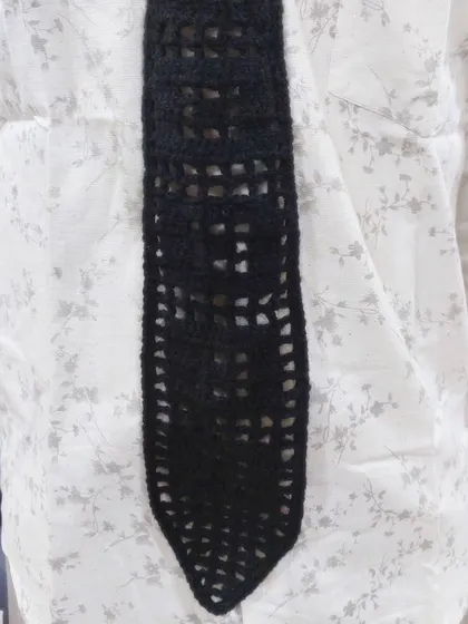 The filet crochet tie styled with a simple white shirt, showing how it can elevate a classic look.