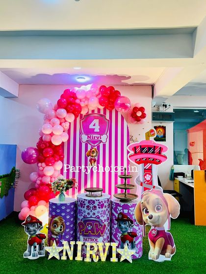 A pink Paw Patrol theme for Nirvi's 4th birthday. We created a fun setup with a striped backdrop, a pink balloon arch, and cutouts of the Paw Patrol characters, including Skye and Marshall.