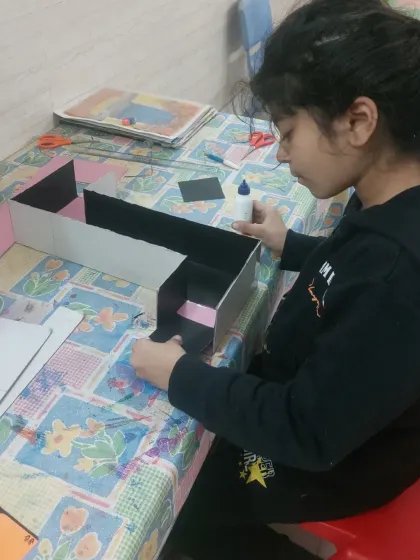 A student focused on constructing her periscope. These projects help develop fine motor skills and the ability to follow instructions, all while having fun.
