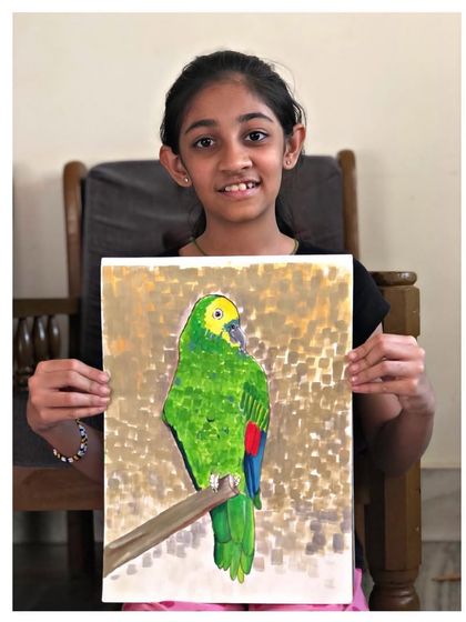 The student with her vibrant parrot painting. Her work is a great example of the beautiful and realistic art my students create.
