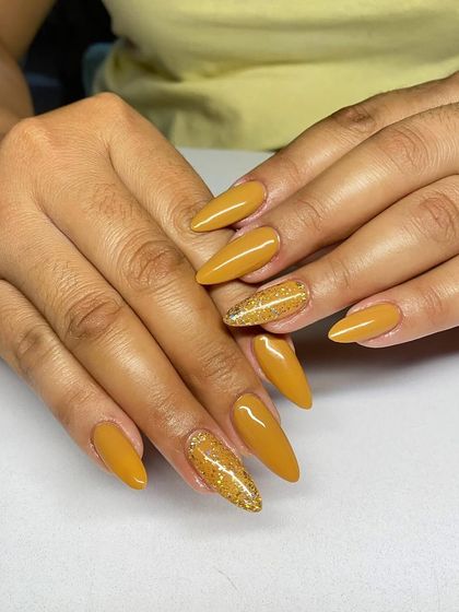 A warm and sunny set of almond-shaped extensions in a solid mustard yellow, with a gold glitter accent nail.