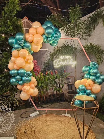 Another angle of the modern teal and peach birthday setup. This view highlights the hexagonal frame and the placement of the neon sign within the lush garden setting.