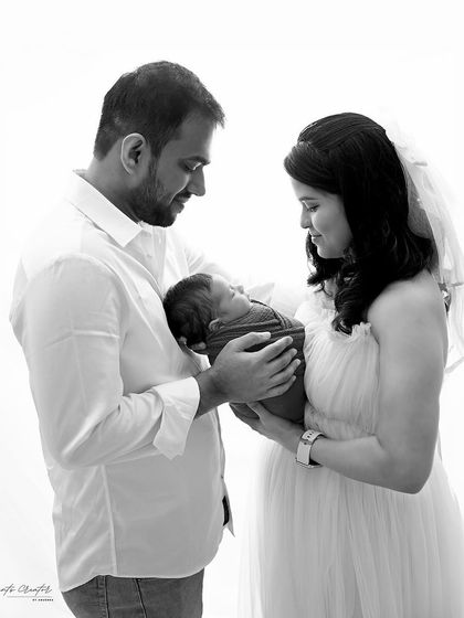 A timeless black and white version of a new family's first portrait. The high-key lighting and lack of color emphasize the emotion and connection between the parents and their baby.