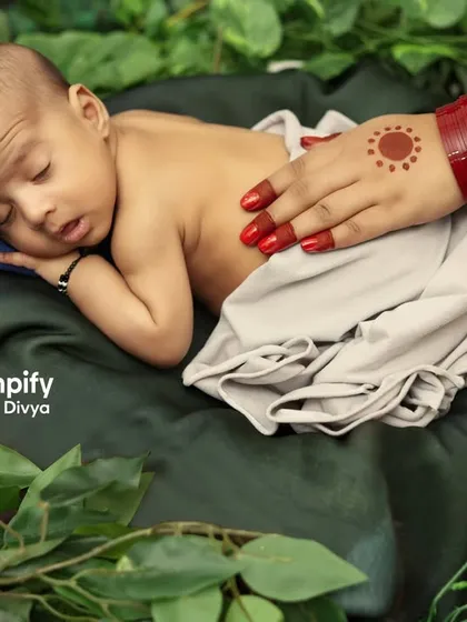 A sleeping newborn rests peacefully, watched over by the symbolic hands of Shiva and Parvati. This is a deeply meaningful concept for families welcoming a baby during Saavan.