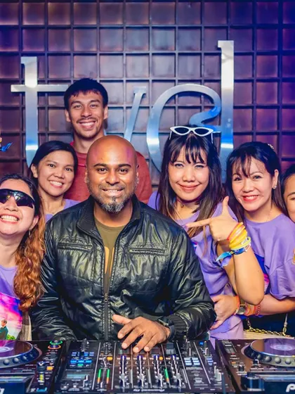 A group of fans in matching shirts at the DJ booth.