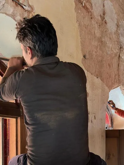 A repeat image of craftsmen restoring the arched windows, highlighting their skill and collaboration.