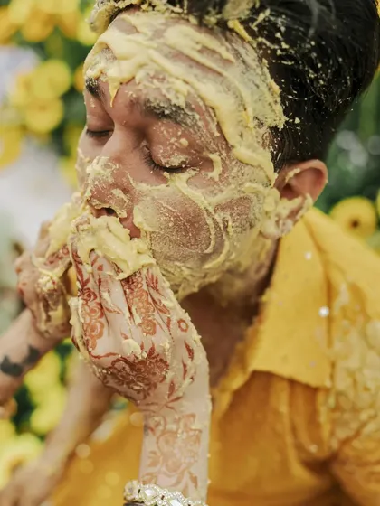 A candid shot of the groom's face covered in turmeric, capturing a moment of playful surrender.