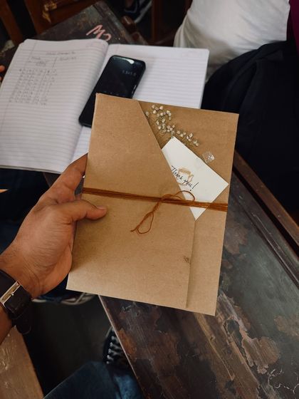 The packaging for a custom order, which included a graphite portrait and a coffee-painted photo strip. The brown paper wrapping and hand-painted card are part of the experience.