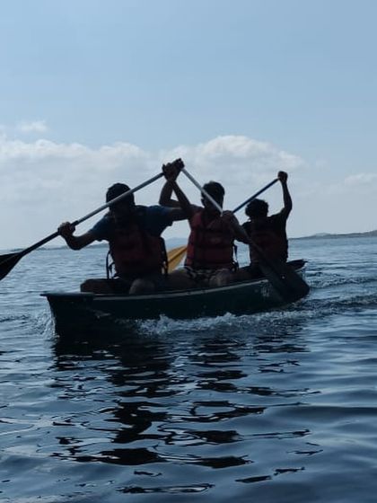 The silhouette of a three-person canoe team paddling in unison captures the spirit of teamwork and adventure.