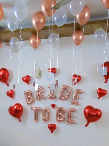 The complete 'BRIDE TO BE' wall decoration, with ceiling balloons in rose gold and white adding to the festive atmosphere.