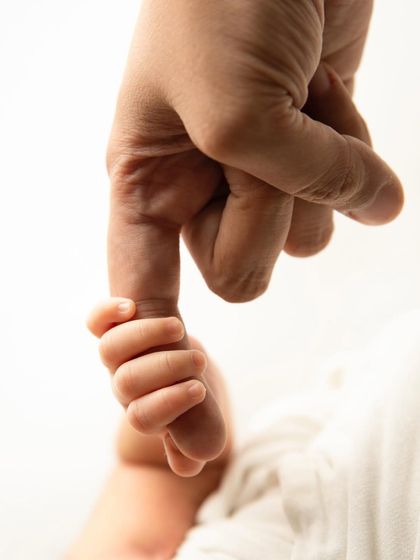 A close up shot capturing a newborn's tiny hand wrapped securely around their parent's finger. This image symbolizes the powerful, instant bond and the start of a lifelong journey together.