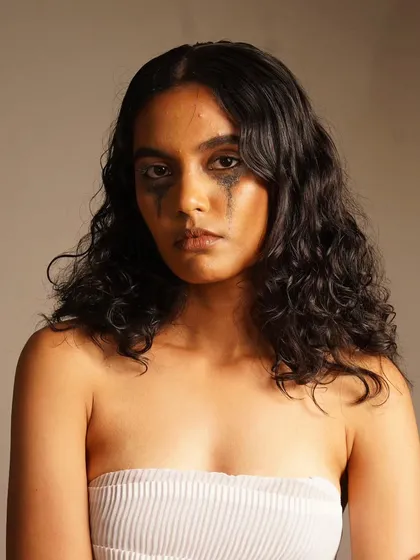 A raw, emotional portrait with smudged, glittery eye makeup to convey a story of vulnerability.