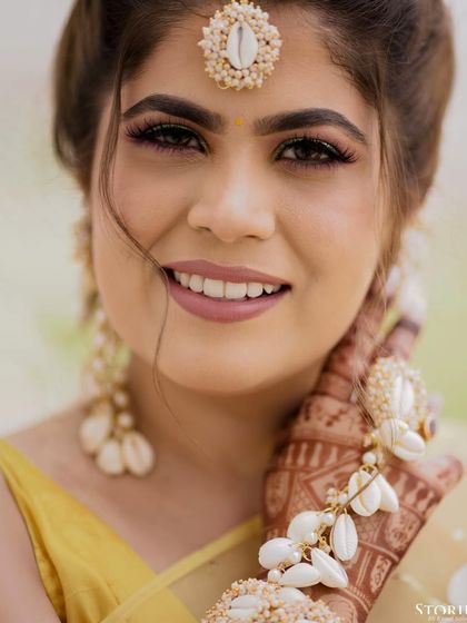 A beautiful close-up of the bride, Bhanvi, during her Haldi ceremony. Her shell jewelry and bright smile capture the joyful and unique spirit of the event.