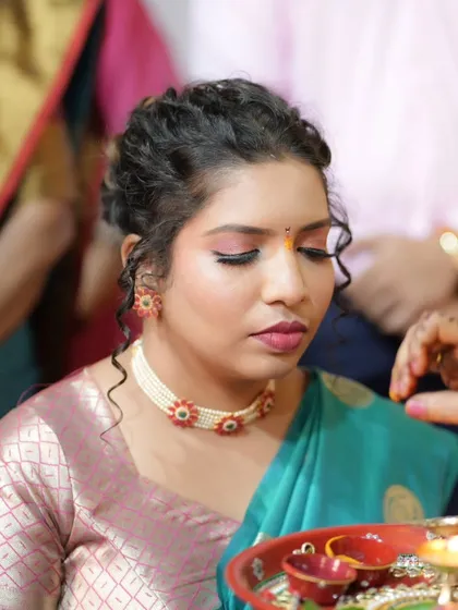 A close-up of the bride during the pooja rituals, her makeup looking fresh and devotional.