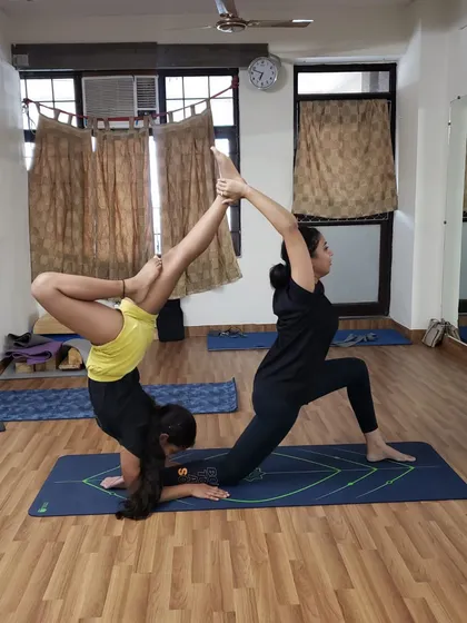As you progress, you will learn more dynamic poses that combine flexibility, strength, and balance. This pose requires the base to be grounded and strong, while the flyer uses core control to hold a split. It shows the athletic potential of acroyoga.