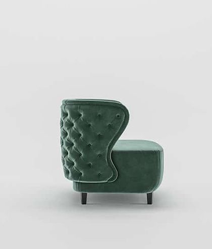 A side view of our green velvet armchair, showcasing the deep tufting on the wingback design, which adds a touch of timeless charm.