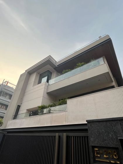 A low-angle view of this modern home, emphasizing its strong geometric forms and the textural contrast of the fluted beige stone. This is a timeless expression of contemporary sophistication.