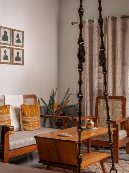 A traditional wooden swing with brass chains becomes a central feature of the living space, viewed here from behind the custom sofa. It adds a playful and nostalgic element to the modern apartment.