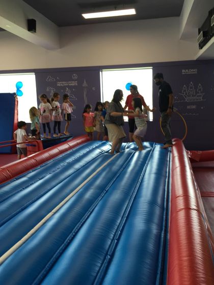 A group of kids lines up for their turn on the Air Track, with our instructors there to guide and assist them.