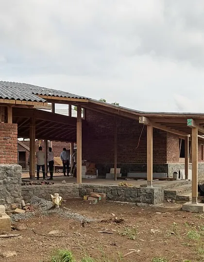 This view shows the interplay of the sloping rooflines and the open verandas of the Kamshet farmhouse. The design breaks down the mass of the building, creating a series of interconnected indoor and outdoor living areas.