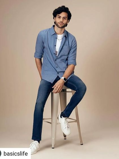 A relaxed and stylish look for the Basics Life campaign. This blue chambray shirt, worn open over a white tee and paired with jeans and white sneakers, is the definition of smart casual menswear.