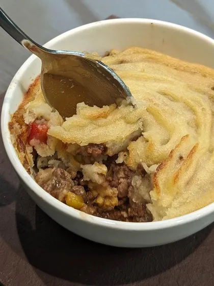A spoonful of warm, comforting Shepherd's Pie. It has a savory minced meat filling topped with creamy mashed potatoes, baked until golden. This dish is ideal as the star of a small dinner party.