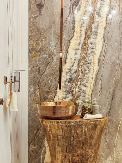 We brought nature indoors with this rustic-chic powder room. A hammered copper vessel sink sits atop a solid wood log pedestal, set against a backdrop of richly veined natural stone.
