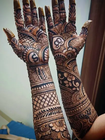 A unique engagement mehandi with the couple's initials "S" and "&" hidden within elaborate heart and paisley shapes.