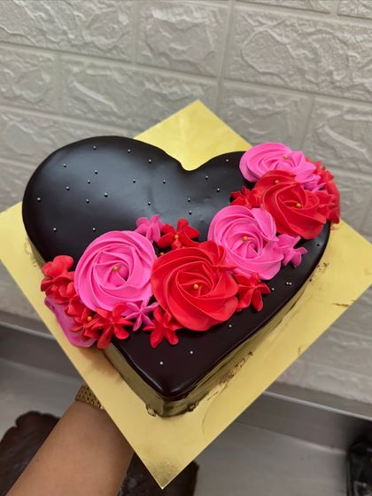 A simple and elegant heart-shaped chocolate cake. It's decorated with beautiful pink and red buttercream roses, making it a classic choice for anniversaries, Valentine's Day, or just to say "I love you."