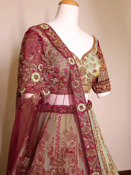A detailed shot of a mint green and maroon embroidered lehenga blouse. The color combination is fresh and perfect for a day wedding.