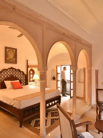 A view into one of the Diwan-e-Khas rooms, where traditional arches frame the space. Each room is appointed with antique-style furniture and offers views into the bylanes of Chandni Chowk, providing a unique and authentic stay.