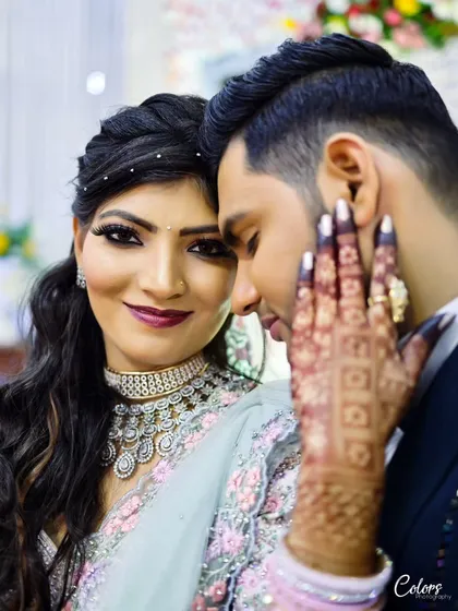A close-up portrait from a reception, focusing on the bride's stunning makeup and jewelry as she shares a moment with her groom.