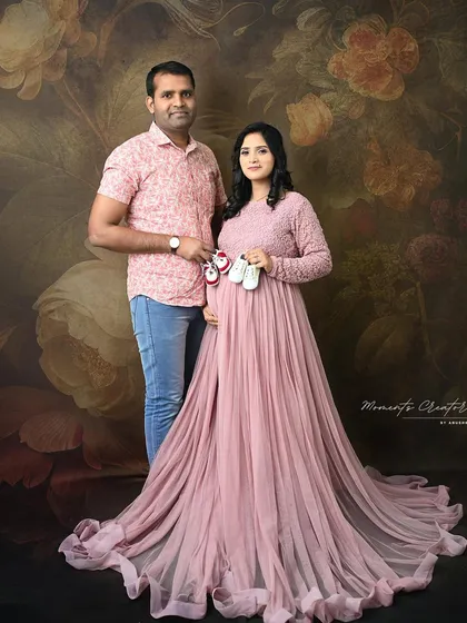 A sweet couple's portrait with a pop of color. The mom-to-be holds two pairs of baby shoes, hinting at the twins they are expecting, one for a boy and one for a girl.