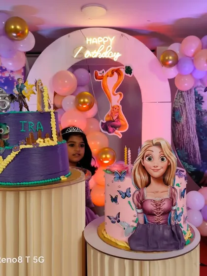 A detailed look at a Tangled themed birthday party, featuring two custom cakes with Rapunzel designs set against a backdrop of the movie's iconic scenes.