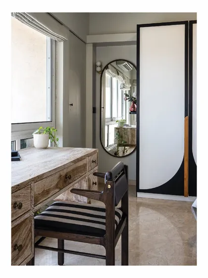 A study table corner in our Powai House project. The rustic wooden desk is paired with a striped chair and an oval mirror. The wardrobe doors feature a unique graphic design, showcasing our love for custom details that make a space special.