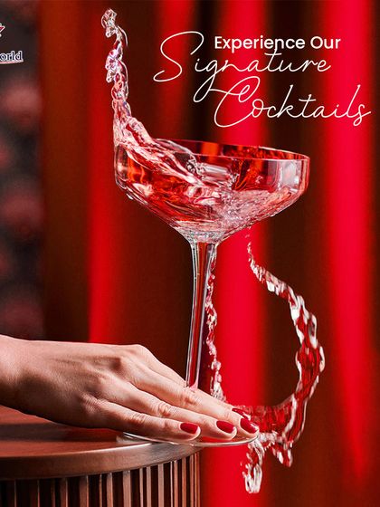 The dramatic splash of our signature red cocktail in a coupe glass. This action shot captures the energy and passion we pour into every single drink we make.