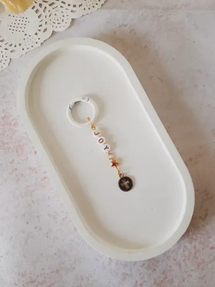 Carry a little 'JOY' with you. This keychain features 'JOY' letter beads, a star, and a cross charm, making it a perfect festive or spiritual accessory.