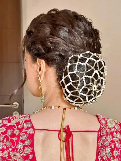 For the bride who wants to ditch the flowers, this textured bun with a pearl net accessory is a stunning alternative. It's unique, elegant, and incredibly detailed.