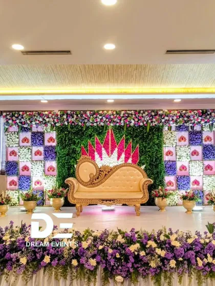 This baby shower stage combines a lush green wall with a stunning floral checkerboard pattern. The elegant chaise lounge and abundant fresh flowers in purple and white create a sophisticated and memorable setting for the mom-to-be.