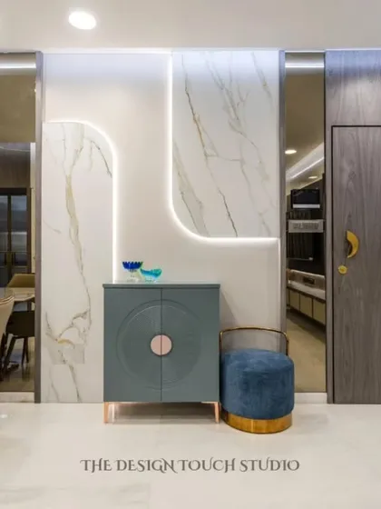 This image highlights a stylish console area next to the main door. The blue cabinet and matching pouf add a pop of color, while the marble wall panel with LED lighting adds a touch of luxury.