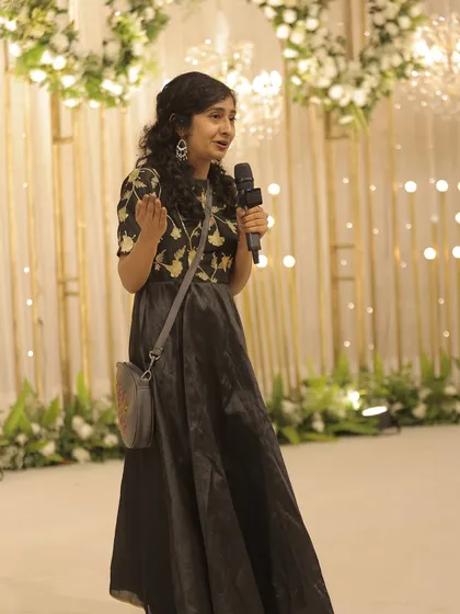 A guest shares a story, with the beautiful floral and light-filled stage behind her.