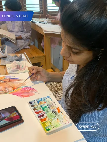 A student works on a colorful portrait, using her phone for reference. Our watercolor courses teach you how to translate a digital image into a beautiful painting.