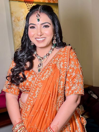 A bold and defined look for a sangeet or cocktail night. The vibrant orange lehenga is paired with a smokey eye and a confident smile.
