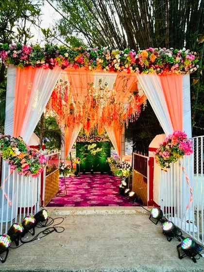 A bright and cheerful entrance for an engagement ceremony. We used peach and white drapes, a colorful floral arch, and a carpet of purple to create a welcoming and festive walkway.