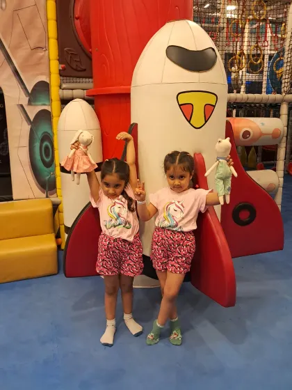 Twin power. Two sisters pose with their dolls in front of our rocket ship play structure.