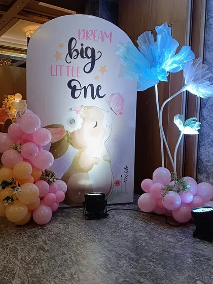 A close-up of the "Dream Big Little One" sign, paired with an adorable bunny illustration and illuminated floral props.