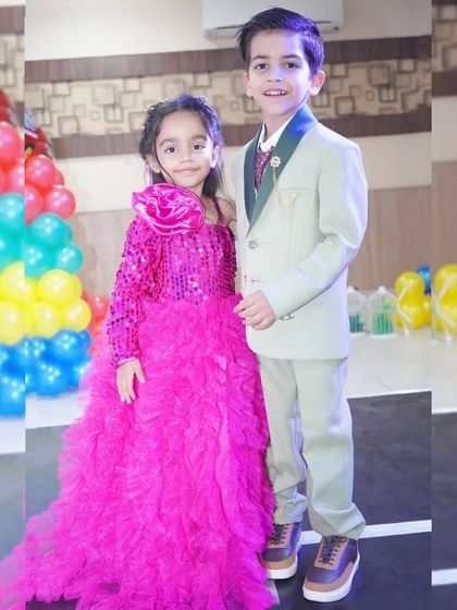 A brother and sister dressed in their party best, posing for a photo during a birthday event.