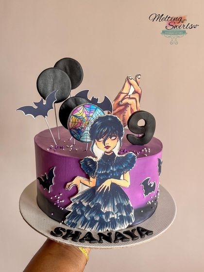 A spooky and stylish Wednesday Addams themed cake. This Belgian chocolate truffle cake is decorated in shades of purple and black, with edible toppers of Wednesday and Thing.