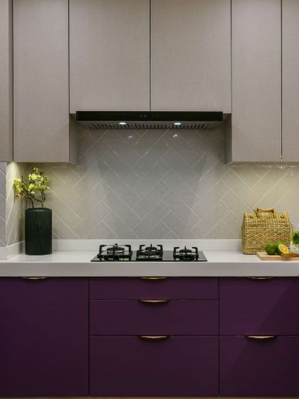 I transformed a closed-in kitchen into this bright and airy haven. Deep aubergine base cabinets with copper handles add a touch of luxury, while the white countertops and herringbone backsplash keep the space fresh and modern.