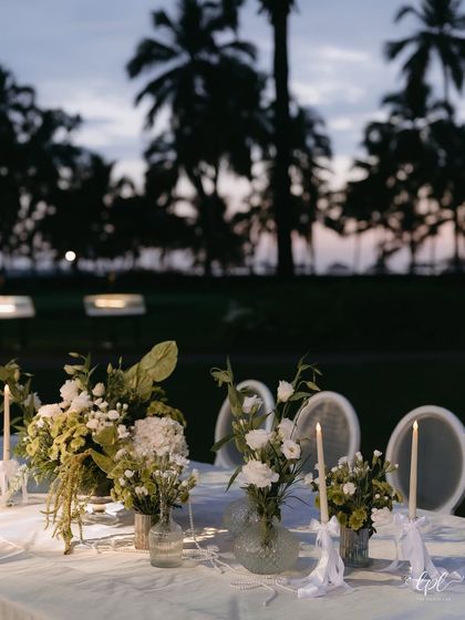 A timeless white tablescape set against the dusky Goan sky. The combination of white linens, classic florals, and candlelight creates an atmosphere of pure elegance.